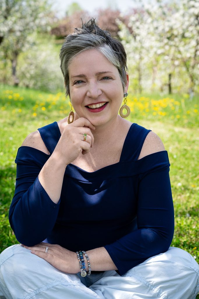 Krystal Houseman seated for a portrait taken outside in an apple orchard